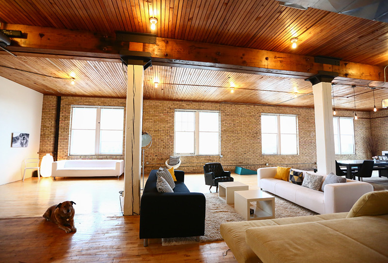 Exemple d'un très grand salon industriel ouvert avec un mur marron, un sol en bois brun et aucune cheminée.