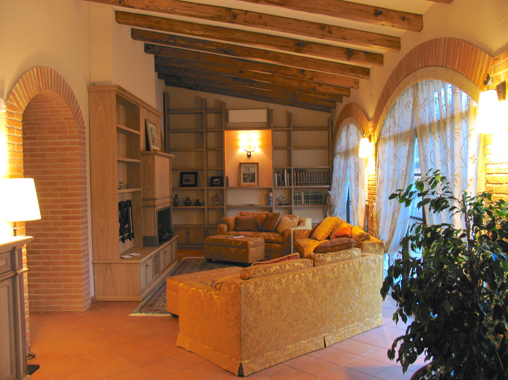 На фото: большая открытая гостиная комната в классическом стиле с с книжными шкафами и полками, бежевыми стенами, полом из терракотовой плитки, стандартным камином, фасадом камина из дерева и мультимедийным центром