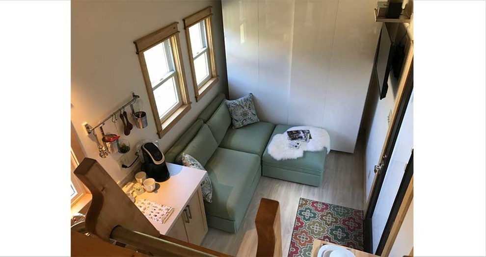 На фото: маленькая изолированная гостиная комната в стиле модернизм с с книжными шкафами и полками, бежевыми стенами, полом из ламината и телевизором на стене без камина для на участке и в саду с