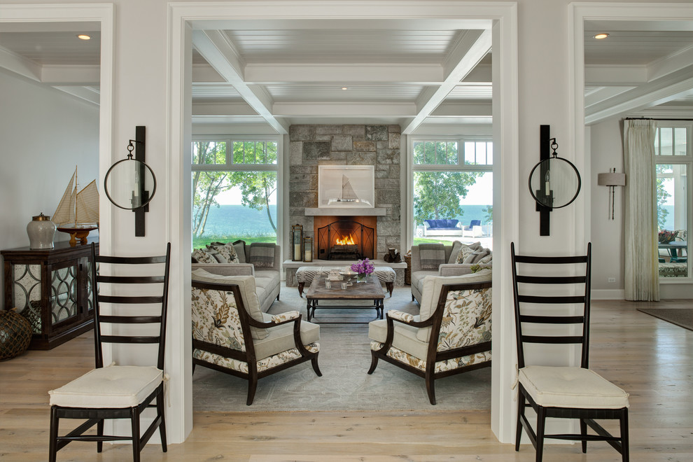 Cette image montre un salon marin avec un mur gris, parquet clair, un manteau de cheminée en pierre et une cheminée standard.
