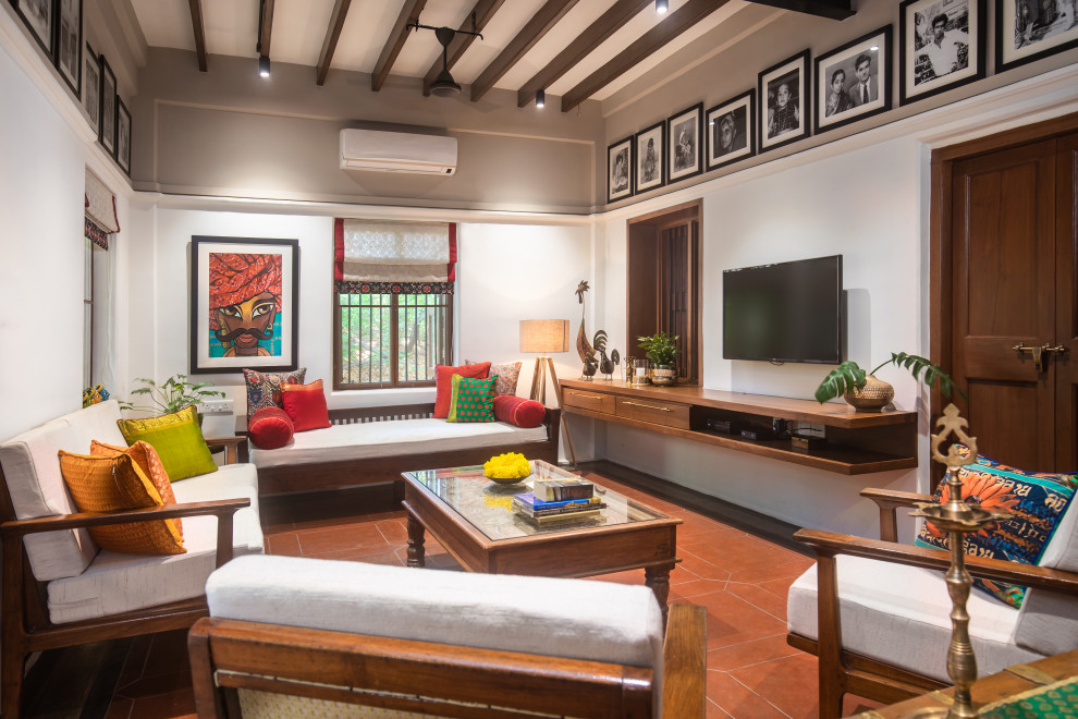 Modernes Wohnzimmer mit weißer Wandfarbe, TV-Wand, rotem Boden und freigelegten Dachbalken in Chennai