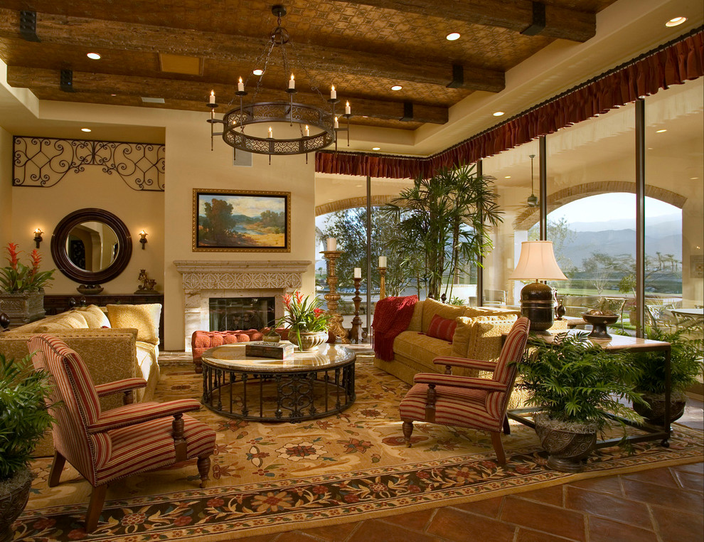 Foto di un soggiorno mediterraneo con pareti beige, pavimento in terracotta, camino classico e cornice del camino in pietra