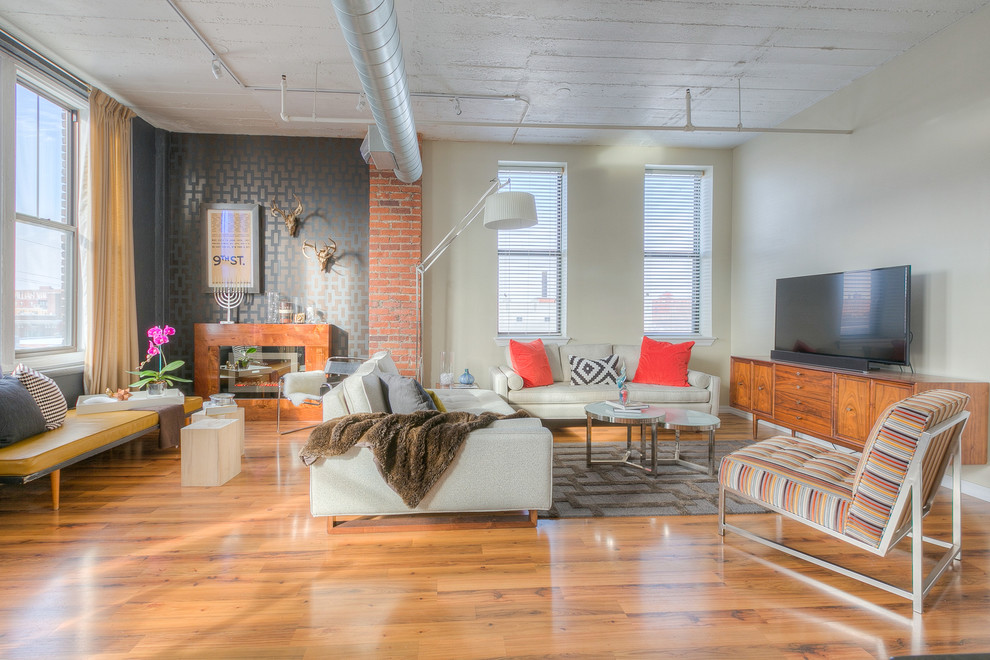 Mittelgroßes, Offenes Industrial Wohnzimmer mit bunten Wänden, braunem Holzboden, freistehendem TV und Gaskamin in Kansas City