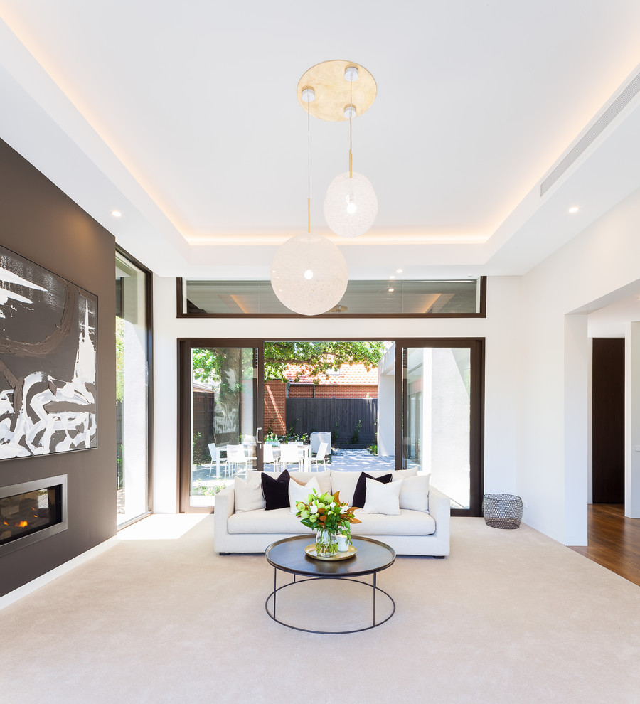 This is an example of a modern enclosed living room in Melbourne with white walls, carpet, a standard fireplace and a metal fireplace surround.