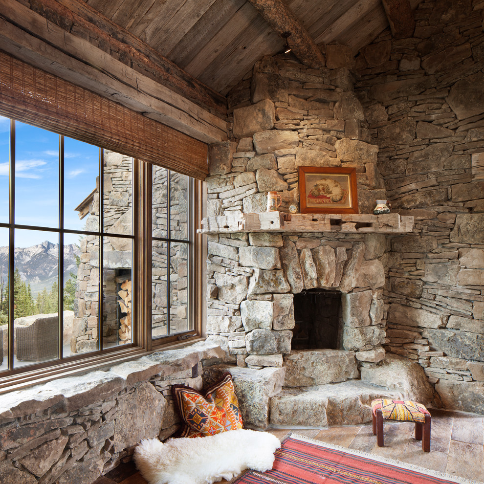 Cette image montre un salon chalet avec un sol en calcaire, une cheminée d'angle et un manteau de cheminée en pierre.