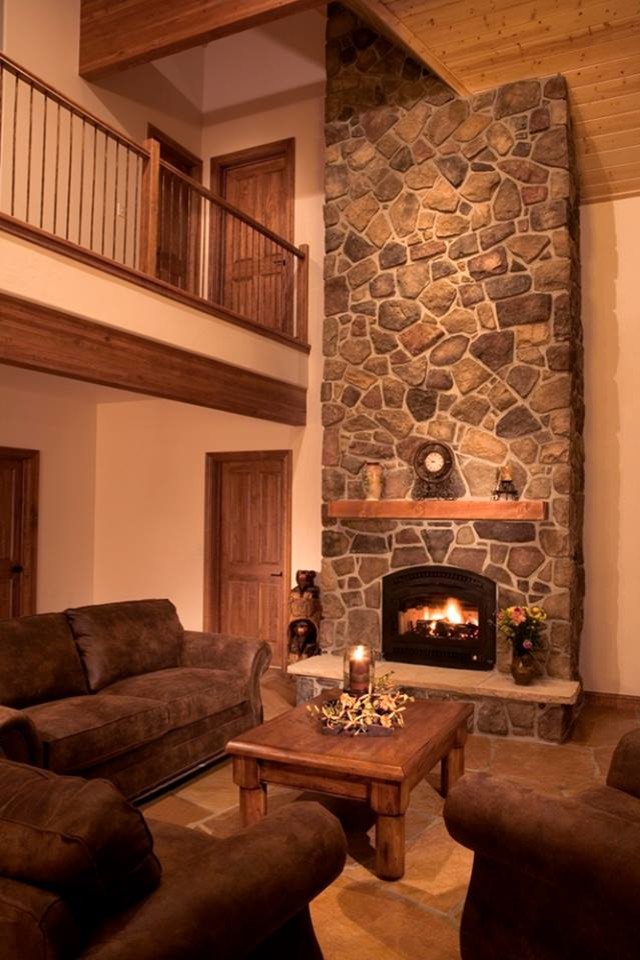 Источник вдохновения для домашнего уюта: большая парадная, открытая гостиная комната в стиле рустика с коричневыми стенами, стандартным камином, фасадом камина из камня и коричневым полом