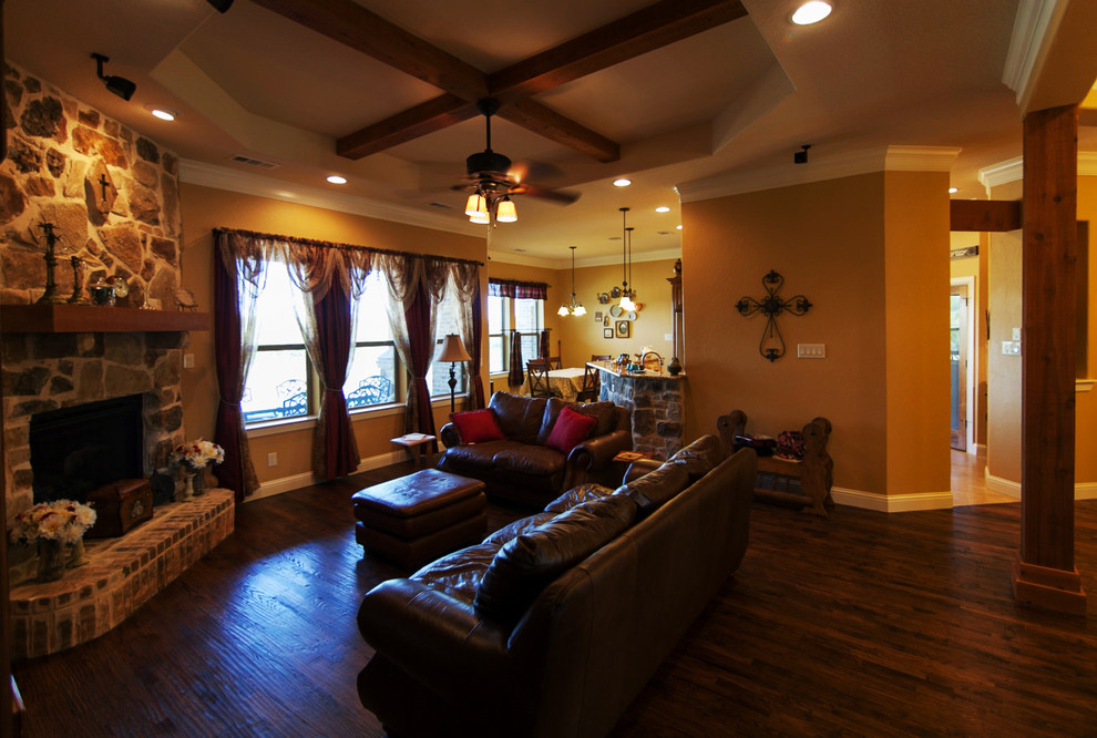 Mittelgroßes, Offenes Klassisches Wohnzimmer mit gelber Wandfarbe, braunem Holzboden, Eckkamin, Kaminumrandung aus Stein und Multimediawand in Dallas