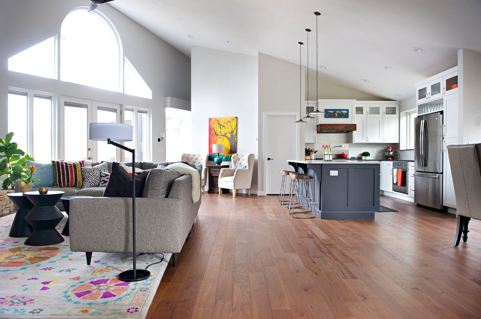 Cette image montre un grand salon traditionnel ouvert avec un mur gris, un sol en bois brun, une cheminée standard, un manteau de cheminée en pierre et un téléviseur indépendant.