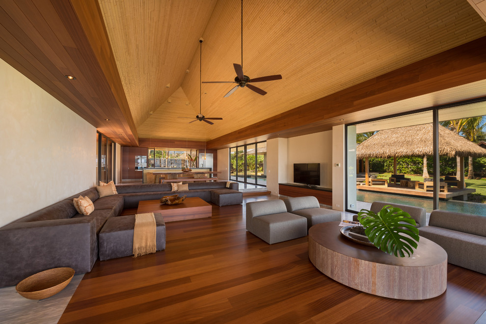 Inspiration for a large world-inspired open plan living room in Hawaii with beige walls, dark hardwood flooring, a freestanding tv and brown floors.