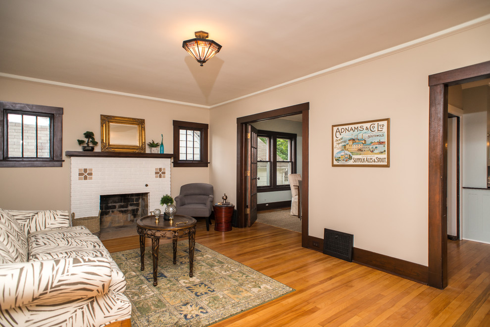 Exemple d'un salon craftsman de taille moyenne et fermé avec une salle de réception, un mur beige, un manteau de cheminée en pierre, un sol en bois brun et une cheminée standard.