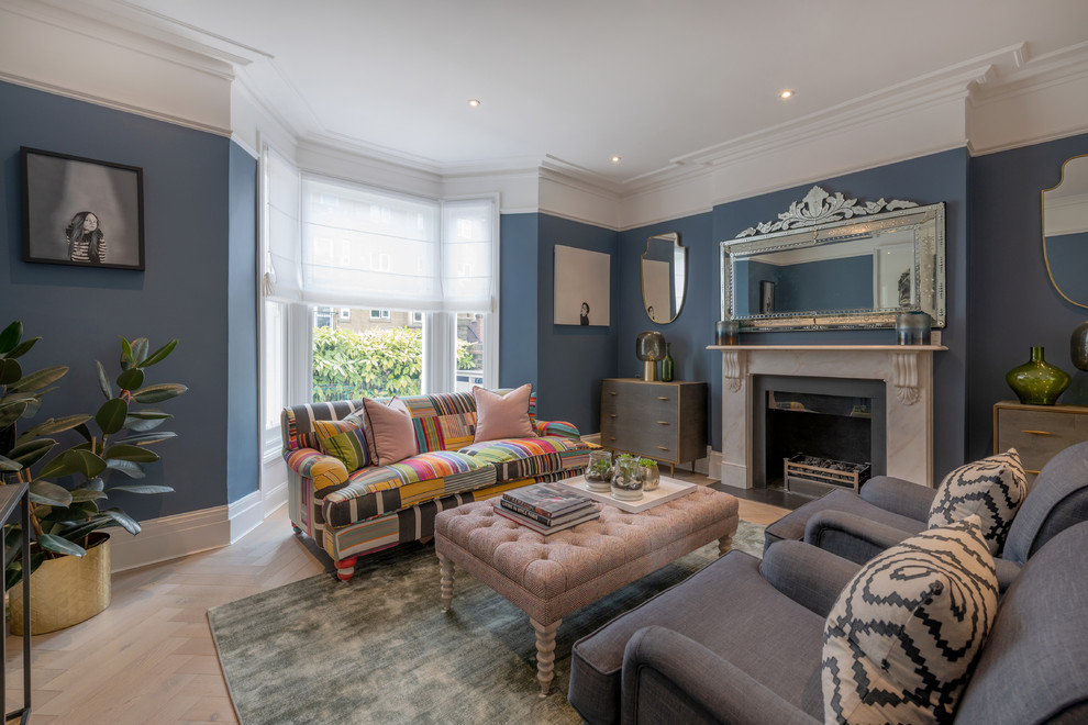 Classic open plan living room in London with blue walls, light hardwood flooring, a standard fireplace and beige floors.