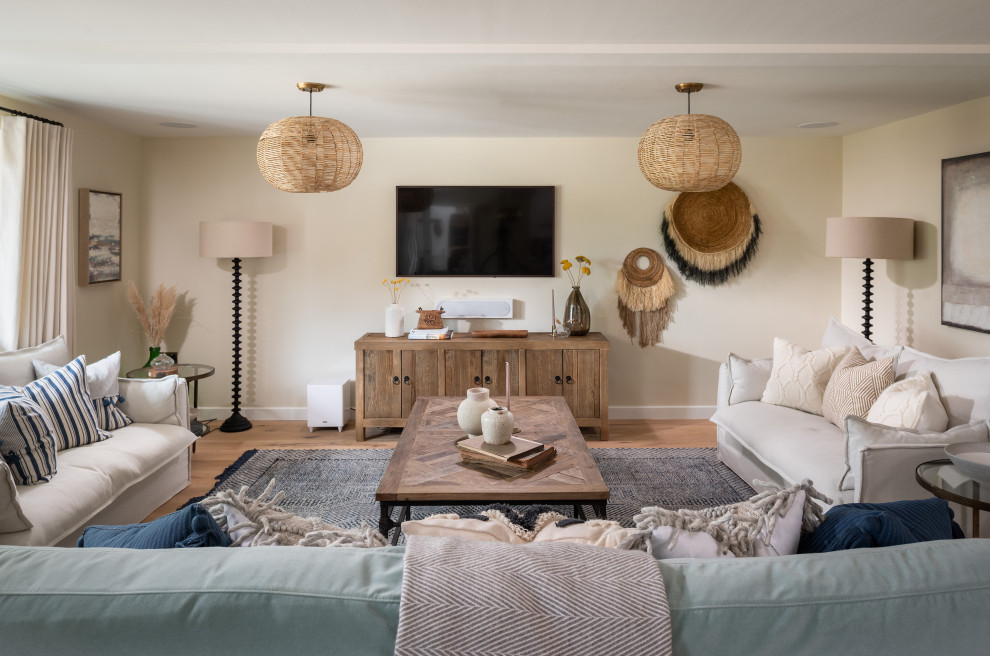 Esempio di un grande soggiorno country con pareti beige, pavimento in legno massello medio e TV a parete