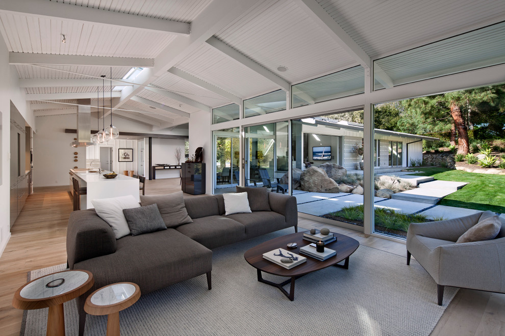 Esempio di un soggiorno moderno di medie dimensioni e aperto con pareti bianche, parquet chiaro e pavimento marrone