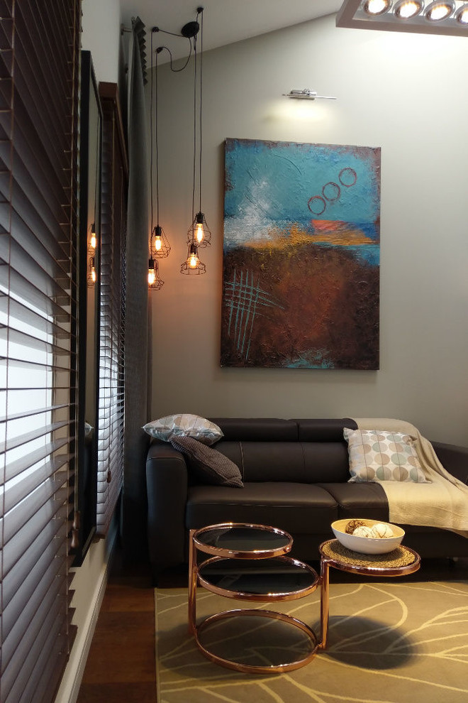 Modelo de salón para visitas abierto moderno pequeño con paredes beige, suelo de madera oscura y televisor colgado en la pared