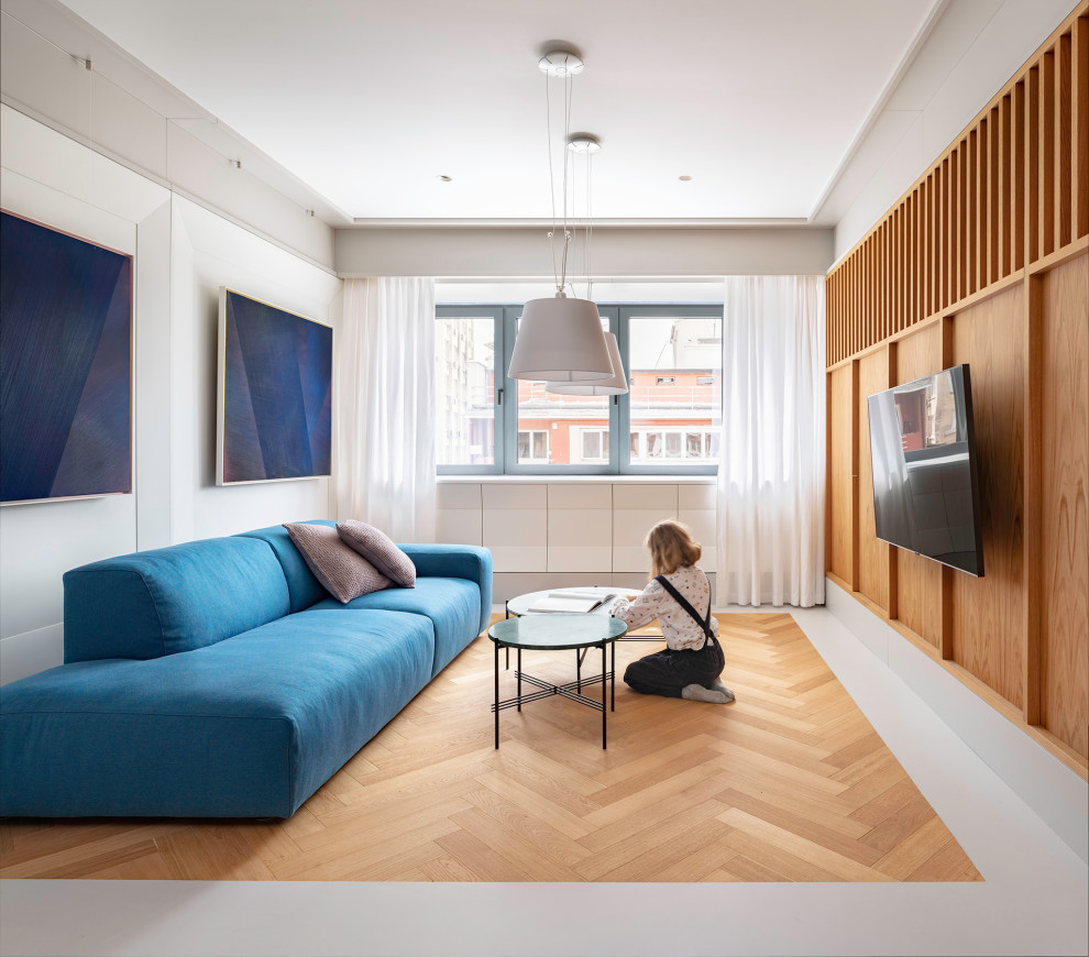 This is an example of a medium sized contemporary open plan living room in London with white walls, medium hardwood flooring, a wall mounted tv and beige floors.