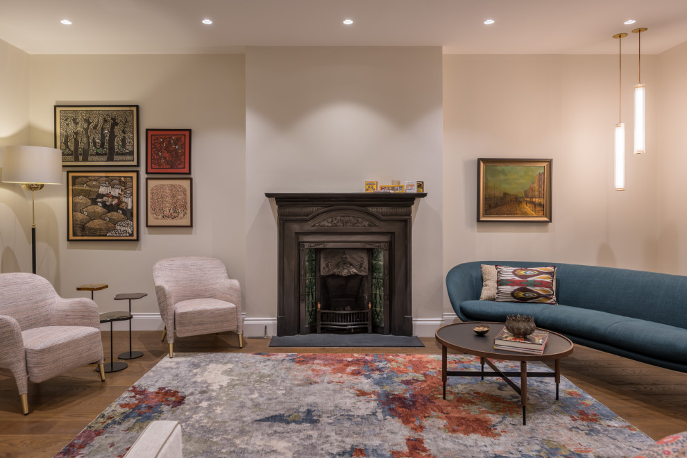 Großes, Repräsentatives, Fernseherloses, Abgetrenntes Stilmix Wohnzimmer mit beiger Wandfarbe, braunem Holzboden, Kamin, Kaminumrandung aus Stein und braunem Boden in London