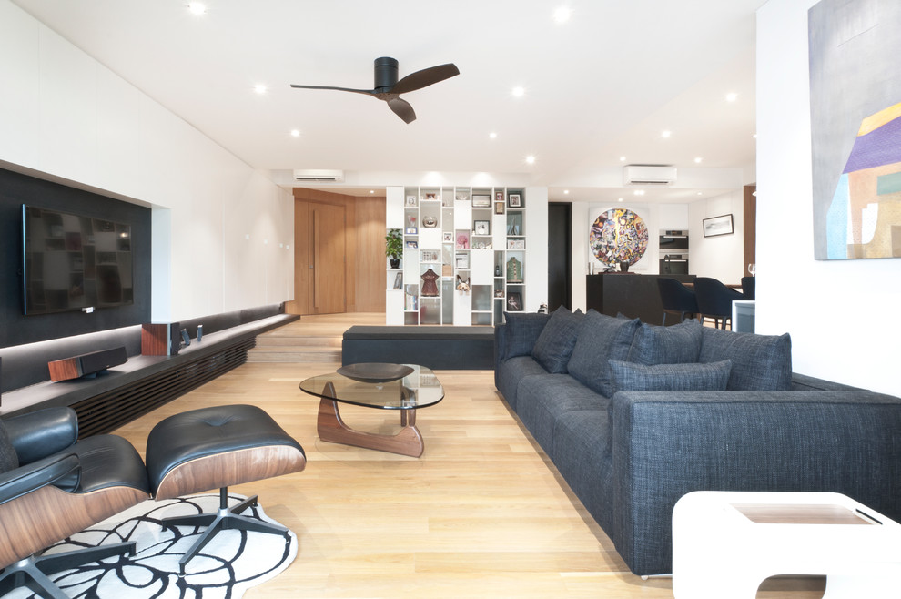 Стильный дизайн: открытая гостиная комната в современном стиле с белыми стенами, светлым паркетным полом и телевизором на стене - последний тренд