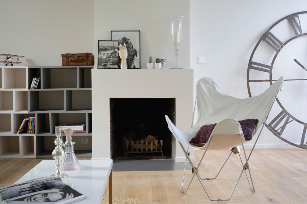 パリにあるコンテンポラリースタイルのおしゃれな独立型リビング (ライブラリー、白い壁、淡色無垢フローリング、標準型暖炉、金属の暖炉まわり) の写真