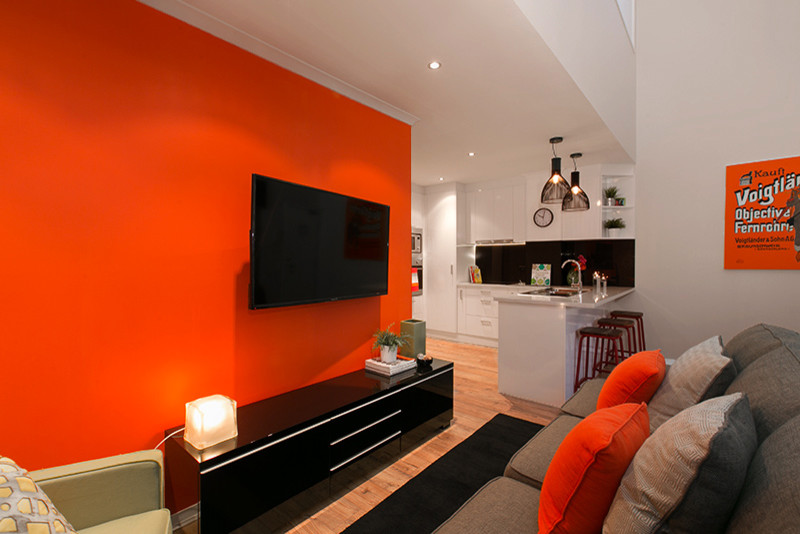 Idéer för att renovera ett mellanstort funkis loftrum, med orange väggar, en väggmonterad TV och bambugolv