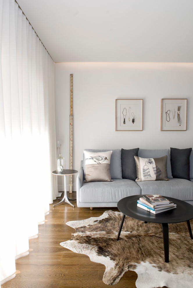 Esempio di un soggiorno minimalista di medie dimensioni e aperto con pareti bianche, pavimento in legno massello medio, nessun camino e TV a parete