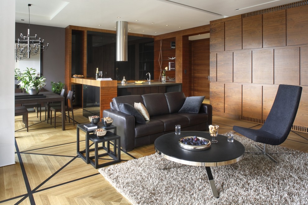 Imagen de salón abierto actual con paredes grises y suelo de madera clara