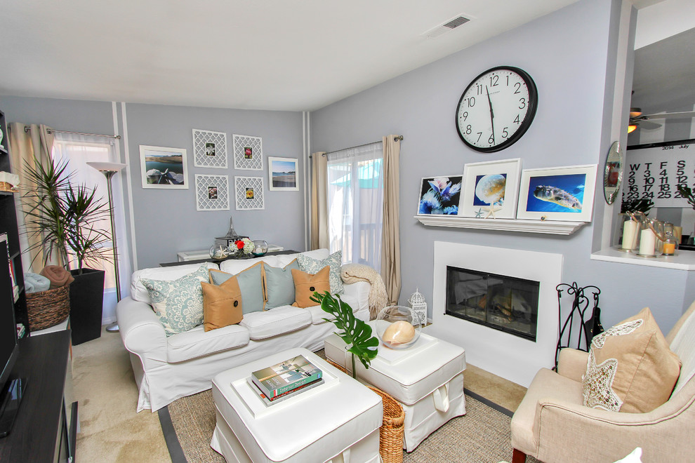 Esempio di un piccolo soggiorno costiero con pareti blu, moquette, camino classico, cornice del camino in legno e TV autoportante
