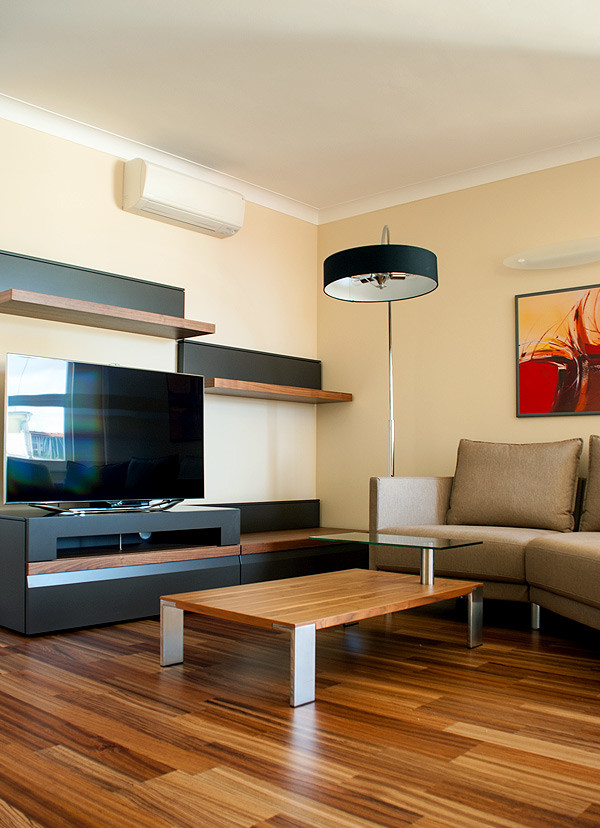 На фото: большая открытая гостиная комната в стиле модернизм с желтыми стенами, деревянным полом и отдельно стоящим телевизором