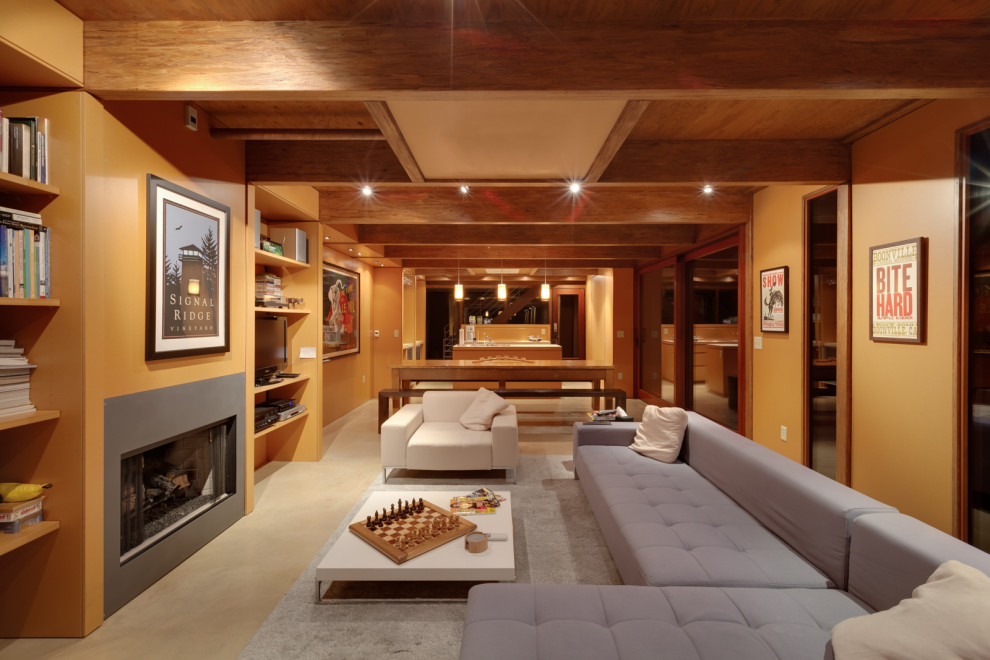 ミルウォーキーにある高級な中くらいなモダンスタイルのおしゃれなLDK (標準型暖炉、埋込式メディアウォール、黄色い壁、コンクリートの床、グレーの床、木材の暖炉まわり) の写真
