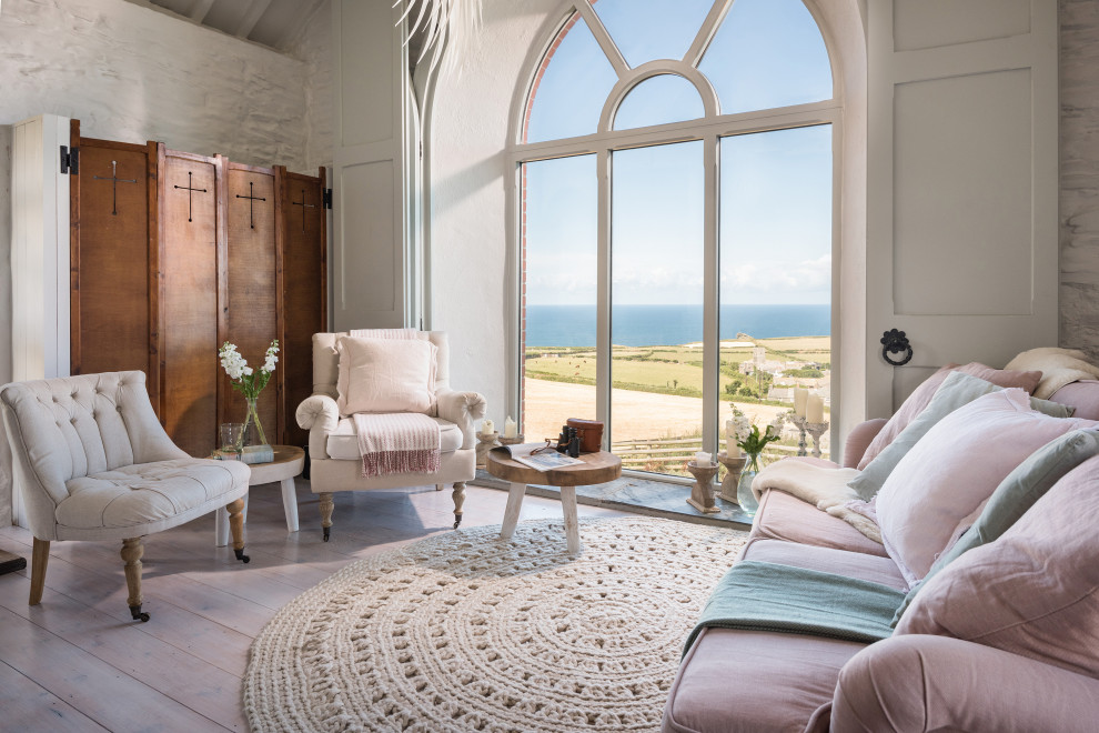 Mittelgroßes, Offenes Maritimes Wohnzimmer mit weißer Wandfarbe, gebeiztem Holzboden, Kamin und weißem Boden in Cornwall