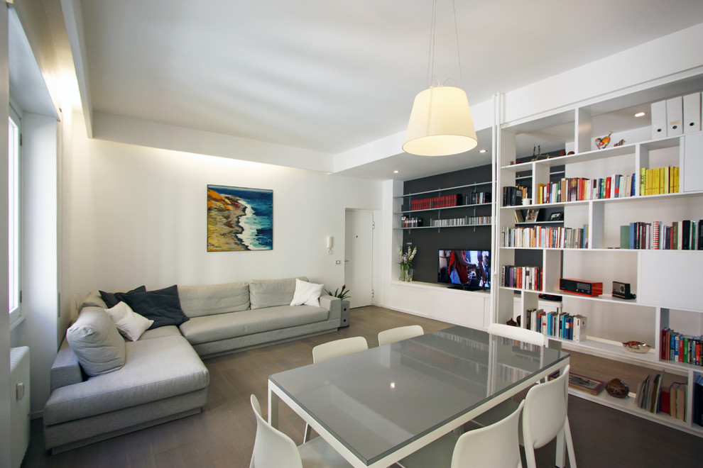 Ejemplo de biblioteca en casa abierta moderna pequeña sin televisor con paredes blancas y suelo de madera en tonos medios