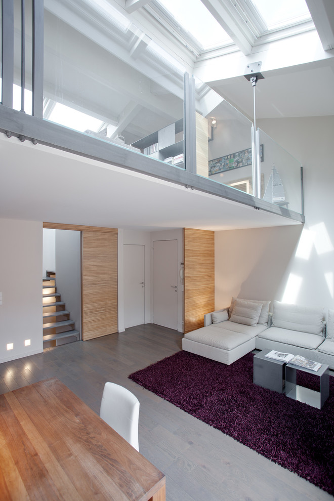 Idée de décoration pour un salon design avec un mur blanc, parquet clair et un escalier.