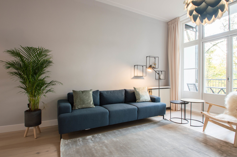 Esempio di un piccolo soggiorno nordico aperto con pareti grigie, parquet chiaro e TV autoportante