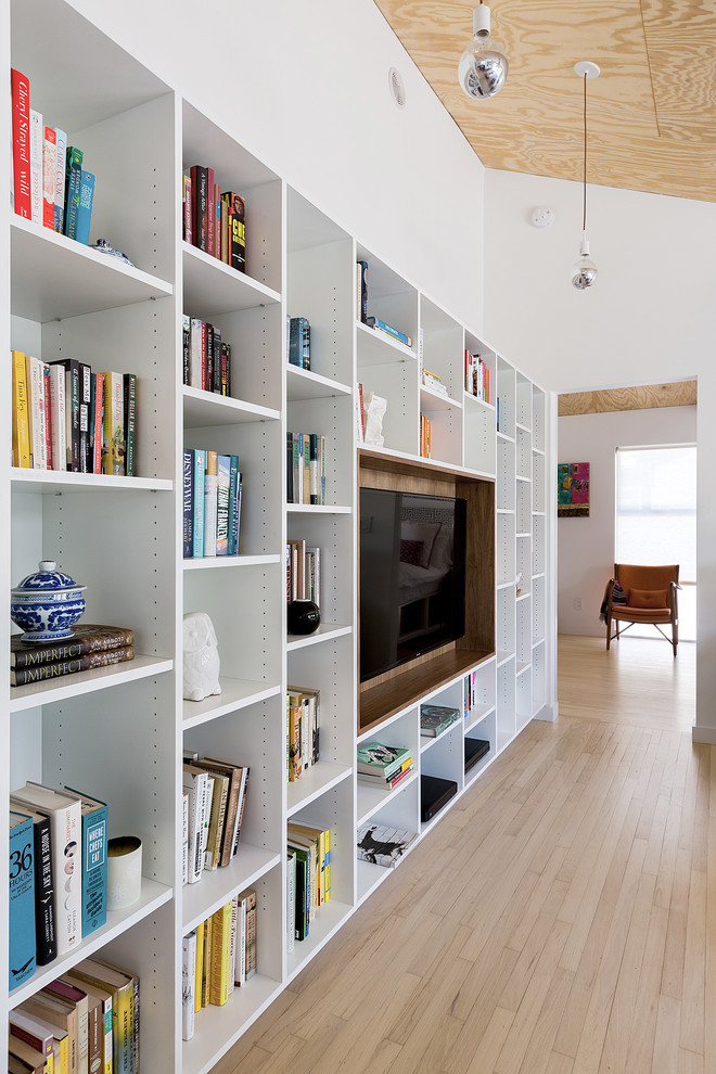 Idée de décoration pour un salon design ouvert avec une bibliothèque ou un coin lecture, un mur blanc, parquet clair et un téléviseur encastré.