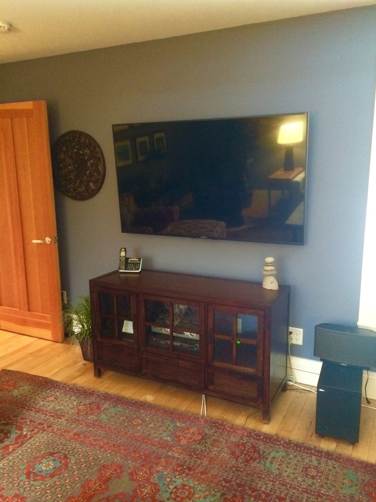Modelo de salón cerrado bohemio de tamaño medio con paredes azules y televisor colgado en la pared