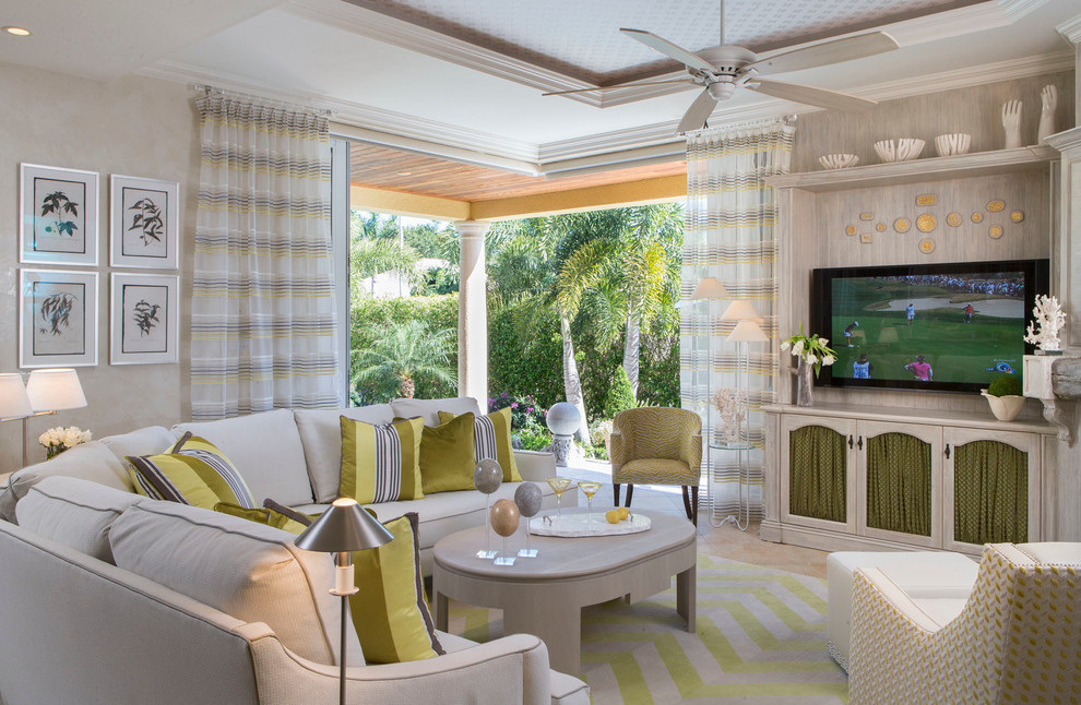 Modelo de salón cerrado tropical grande sin chimenea con televisor colgado en la pared, paredes beige, moqueta y cortinas