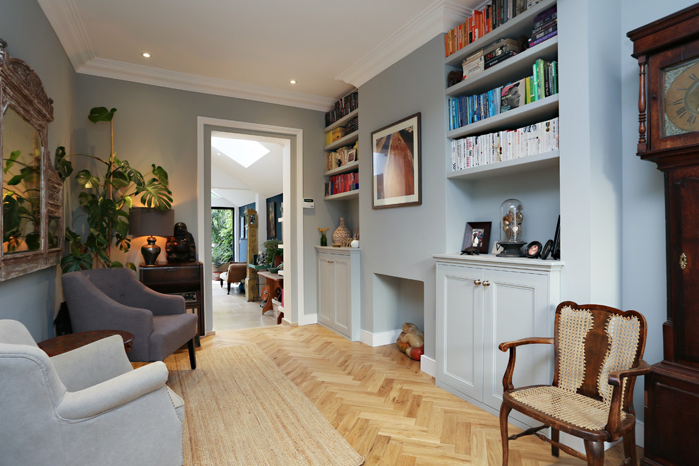 Photo of a large eclectic open plan living room in London with a reading nook, grey walls, light hardwood flooring, no fireplace, a wall mounted tv and beige floors.