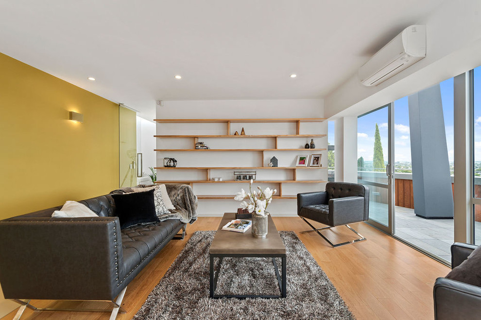 Immagine di un soggiorno design chiuso con pareti gialle e parquet chiaro