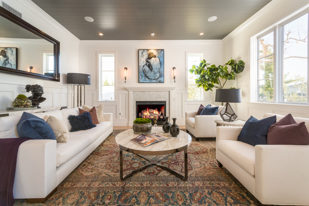 Classic living room in Los Angeles with white walls, light hardwood flooring, a standard fireplace, a tiled fireplace surround, beige floors, a timber clad ceiling and wainscoting.