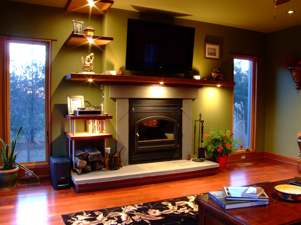 Aménagement d'un salon moderne de taille moyenne et fermé avec un mur vert, un sol en bois brun, une cheminée standard, un manteau de cheminée en béton et un téléviseur fixé au mur.