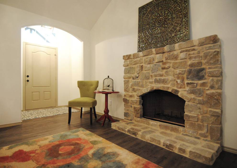 Cette image montre un salon bohème de taille moyenne et ouvert avec un mur blanc, un sol en vinyl, une cheminée standard, un manteau de cheminée en pierre et un téléviseur fixé au mur.