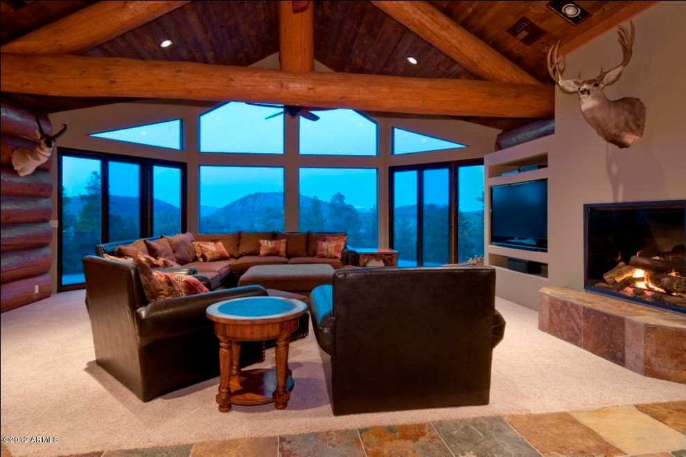 Cette photo montre un grand salon montagne avec un mur beige, un sol en ardoise, une cheminée standard, un téléviseur encastré et un sol multicolore.