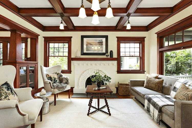 Inspiration pour un grand salon craftsman avec un mur beige, un sol en bois brun, une cheminée standard, un manteau de cheminée en plâtre, aucun téléviseur et un sol marron.