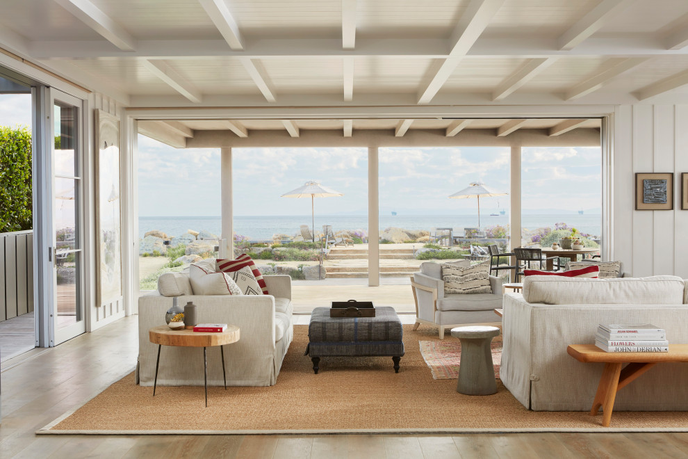 Example of a beach style medium tone wood floor, brown floor, exposed beam and wall paneling living room design in Santa Barbara with white walls