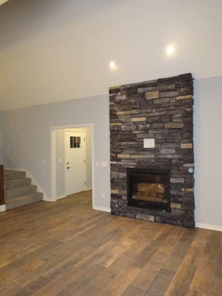 Photo of a medium sized classic open plan living room in Milwaukee with grey walls, porcelain flooring, a standard fireplace, a stone fireplace surround and a wall mounted tv.