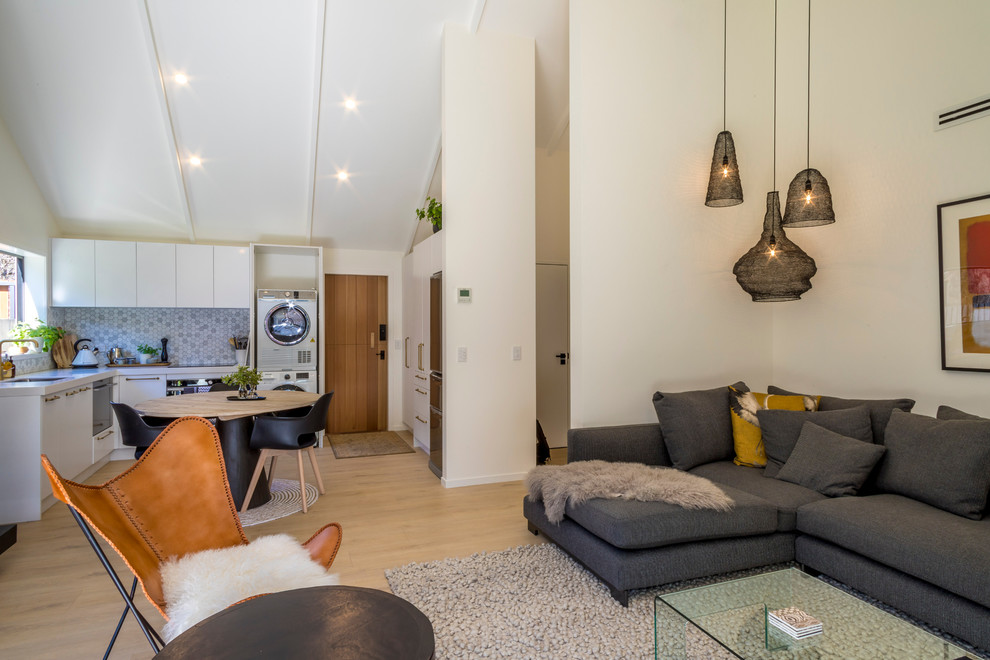 Kleines, Offenes Modernes Wohnzimmer mit weißer Wandfarbe, Laminat, Kamin, Kaminumrandung aus Holz, TV-Wand und beigem Boden in Sonstige
