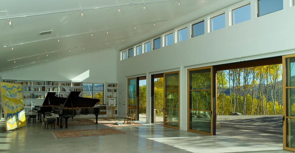 Esempio di un soggiorno contemporaneo stile loft con sala della musica, pareti bianche e pavimento in cemento