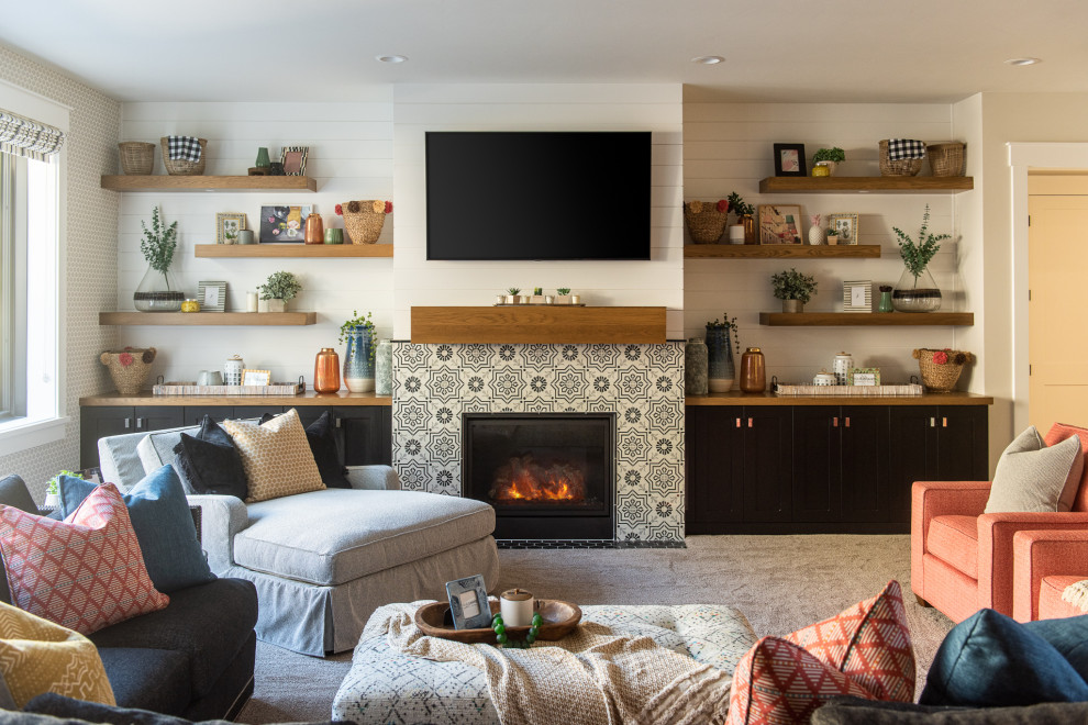 На фото: гостиная комната в стиле неоклассика (современная классика) с белыми стенами, ковровым покрытием, стандартным камином, фасадом камина из плитки, телевизором на стене и серым полом