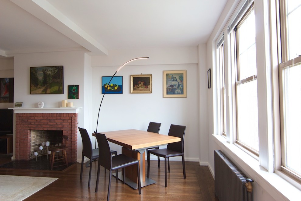Bild på ett mellanstort vintage loftrum, med ett finrum, vita väggar, mörkt trägolv, en standard öppen spis, en spiselkrans i tegelsten, en fristående TV och brunt golv
