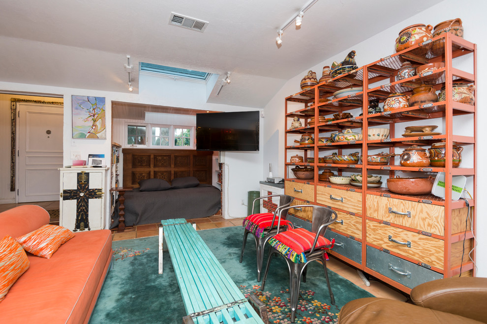 Foto de salón bohemio de tamaño medio sin chimenea con paredes blancas, suelo de baldosas de terracota y televisor colgado en la pared