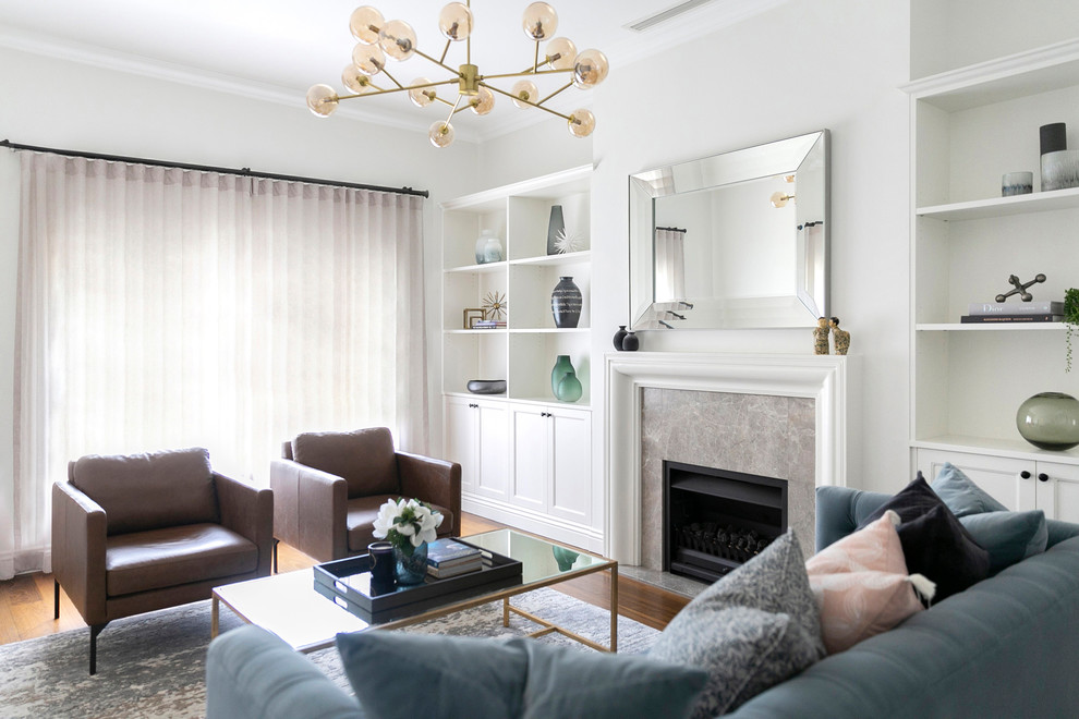 Свежая идея для дизайна: гостиная комната в стиле неоклассика (современная классика) с белыми стенами, паркетным полом среднего тона, стандартным камином, фасадом камина из камня и коричневым полом - отличное фото интерьера